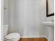 Neat powder room featuring a pedestal sink and toilet, complemented by wood-look flooring at 7818 Spungold St, Raleigh, NC 27617