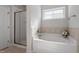 Bright bathroom with a shower and separate tub offers a relaxing space with natural light from a window at 96 Foxtail Ct, Clayton, NC 27520
