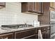 Close up of a gas range with subway tile backsplash, dark cabinets, and stainless appliances at 1029 Benay Rd, Morrisville, NC 27560