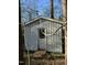 Small white shed with a single door and window surrounded by trees and foliage at 1116 Shadywood Ln, Raleigh, NC 27603