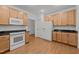 Cozy kitchen features wooden cabinets, granite countertops, laminate floors, and white appliances at 1146 Blue Bird Ln, Wake Forest, NC 27587