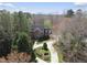 Stunning aerial view of a brick home with a circular driveway surrounded by lush greenery and mature trees at 12101 Lockhart Ln, Raleigh, NC 27614
