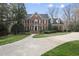 Stately brick home with manicured landscaping, mature trees, and a circular driveway at 12101 Lockhart Ln, Raleigh, NC 27614