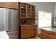 This kitchen has stainless fridge, wood cabinets, a wine rack, and glass door storage at 1705 Mcrae Pl, Hillsborough, NC 27278