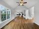 Open-concept living room with hardwood floors, natural light, ceiling fan, and view of kitchen and staircase at 2012 Castana Ct, Willow Springs, NC 27592