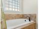 A cozy bathtub nestled beneath a window with decorative tile surround and stylish fixtures at 203 Streamside Dr, Sanford, NC 27330