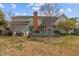 Rear exterior of the house showcases deck, brick chimney, and well-maintained lawn at 205 Parliament Pl, Dunn, NC 28334