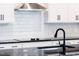 Modern kitchen with white cabinets, granite countertops, subway tile backsplash, and stainless steel range hood at 207 Golfview Ave, Benson, NC 27504