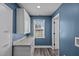 Bright laundry room featuring blue walls, white cabinets, and a window for natural light at 3005 Lewy Ln, Rocky Mount, NC 27801