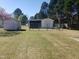 Image shows two sheds or outbuildings surrounded by a chain-link fence on a grassy lot at 3226 Powhatan Rd, Clayton, NC 27527
