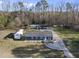 An aerial view of a charming blue home with a long driveway surrounded by bare trees on a sunny day at 352 Leonard Rd, Louisburg, NC 27549