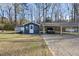 A blue outbuilding and carport sit on a lot in a residential area with mature trees at 352 Leonard Rd, Louisburg, NC 27549