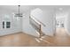 Sunlit entryway boasts modern light fixture, natural wood staircase, and hardwood floors at 5057 Lundy Dr # 101, Raleigh, NC 27606