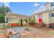 Charming home exterior with a bright red door, trellis, beautiful plantings, and well-kept landscaping at 603 W Main St, Haw River, NC 27258