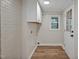 Laundry room with washer and dryer hookups, wood flooring, and painted brick wall at 605 Canterbury Rd, Sanford, NC 27330