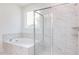 Bright bathroom with a tub and a separate shower enclosed with glass doors and marble-style tile at 63 Tee Time Ter, Benson, NC 27504