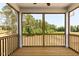 Screened porch with wood flooring, a black railing, and a view of a grassy area with tall trees at 63 Tee Time Ter, Benson, NC 27504