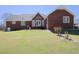 Brick home featuring well-maintained lawn, rear patio, and mature landscaping at 703 E Stanley St, Four Oaks, NC 27524