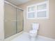 Bathroom with a shower with glass doors, white tiled floor, and toilet at 703 E Stanley St, Four Oaks, NC 27524