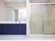 Bathroom featuring a white tiled floor, blue cabinets and a glass door shower at 703 E Stanley St, Four Oaks, NC 27524