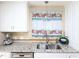 Updated kitchen showcasing a stainless steel sink, granite countertops, and charming floral curtains at 703 E Stanley St, Four Oaks, NC 27524