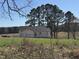 This exterior shows a newly constructed home in a pastoral setting with a large field and trees at 9600 Stallings Rd, Spring Hope, NC 27882