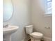 A well-lit powder room features a pedestal sink, toilet, and round mirror, designed for convenience at 98 Tee Time Ter, Benson, NC 27504