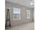 Neutral bedroom with two large windows allowing natural light into the room and a dark lamp in the corner at 1046 Upchurch Farm Ln, Cary, NC 27519