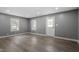 Inviting living room featuring gray walls, modern flooring, natural light from two windows, and a white back door at 1103 Gaston St, Smithfield, NC 27577