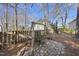A backyard swing set sits on a stone surface, surrounded by a wooden fence and trees on a sunny day at 1301 Merrington Cir, Raleigh, NC 27615