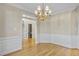 Elegant dining room with hardwood floors, classic wainscoting, and a stylish chandelier fixture at 1301 Merrington Cir, Raleigh, NC 27615