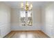 Elegant dining room boasts hardwood floors, wainscoting, chandelier, and natural light at 1301 Merrington Cir, Raleigh, NC 27615