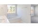 Bright bathroom featuring a soaking tub beneath a large window and double vanity with quartz countertop at 172 Kobus Ct, Garner, NC 27529