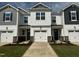 New townhomes featuring attached garages, black shutters, and light-colored siding, creating a modern and appealing facade at 18 Twin Birch Dr, Angier, NC 27501