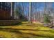 Sloping backyard with retaining wall, trees, and distant seating at 201 Adams Way, Chapel Hill, NC 27516