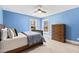 Bright bedroom with blue walls, a wooden bed frame, and natural light from two windows at 201 Adams Way, Chapel Hill, NC 27516