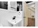 Bright bathroom with a white pedestal sink, dark fixtures, and open doorway to the hallway with stairs at 2120 Cokey Rd, Rocky Mount, NC 27801