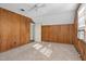 Bedroom featuring wood paneled walls, neutral carpet, and a ceiling fan, with an open doorway to another room at 2120 Cokey Rd, Rocky Mount, NC 27801