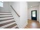 Bright staircase featuring white risers and wood treads leading to a dark-colored door at 280 Beacon Dr, Pittsboro, NC 27312