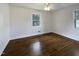 Bright bedroom with gleaming hardwood floors, white walls, and ample natural light from two windows at 300 Perry St, Rolesville, NC 27571