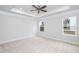 Bright bedroom with a ceiling fan, neutral carpet, tray ceiling, and two sunny windows at 316 Hopewell Branch Ct, Smithfield, NC 27577