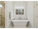 Bathroom featuring freestanding tub, large window, and glass shower at 321 Nottingham Dr, Chapel Hill, NC 27517