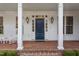 Elegant blue front door framed by white pillars and windows, with sconces and brick steps at 321 Nottingham Dr, Chapel Hill, NC 27517
