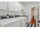 Efficient laundry room with modern washer and dryer, white cabinets, and black and white tile floor at 321 Nottingham Dr, Chapel Hill, NC 27517