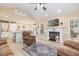 Bright, open-concept living space featuring a fireplace, modern ceiling fan, light wood flooring, and seamlessly connected kitchen at 35 Wickersham Way, Louisburg, NC 27549