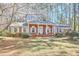 Classic red brick home with white trim, a cozy porch, and a lush front lawn with mature trees at 3613 Hope Valley Rd, Durham, NC 27707