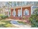 Brick home featuring covered front porch adorned with columns, manicured landscaping, and curved walkway at 3613 Hope Valley Rd, Durham, NC 27707
