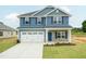 Two-story home featuring blue siding, a white garage door, stone accents, and a well-manicured lawn at 396 Hopewell Branch Ct, Smithfield, NC 27577