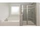 Bathroom with a soaking tub, glass-enclosed shower, and gray tile accents at 410 Hopewell Branch Ct, Smithfield, NC 27577