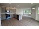 Open kitchen boasts gray cabinets, stainless appliances, and island with granite countertops overlooking the living area at 6401 Granite Quarry Dr, Raleigh, NC 27610